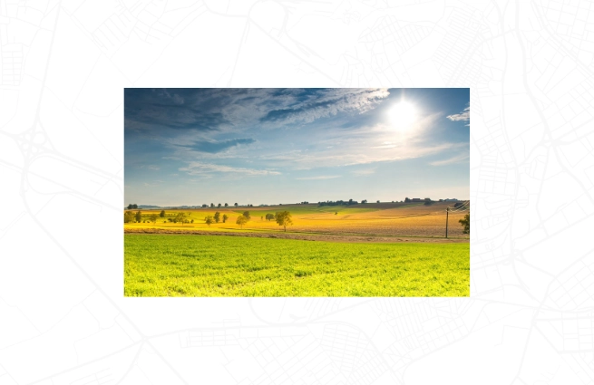 Offene Agrarlandschaft mit Ackerflächen, Feldgehölzen und weitem Horizont